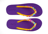 Purple flip-flops with colorful bead embellishments on a white background